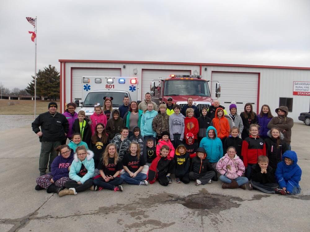 Young students gather next to an ambulance and fire truck.