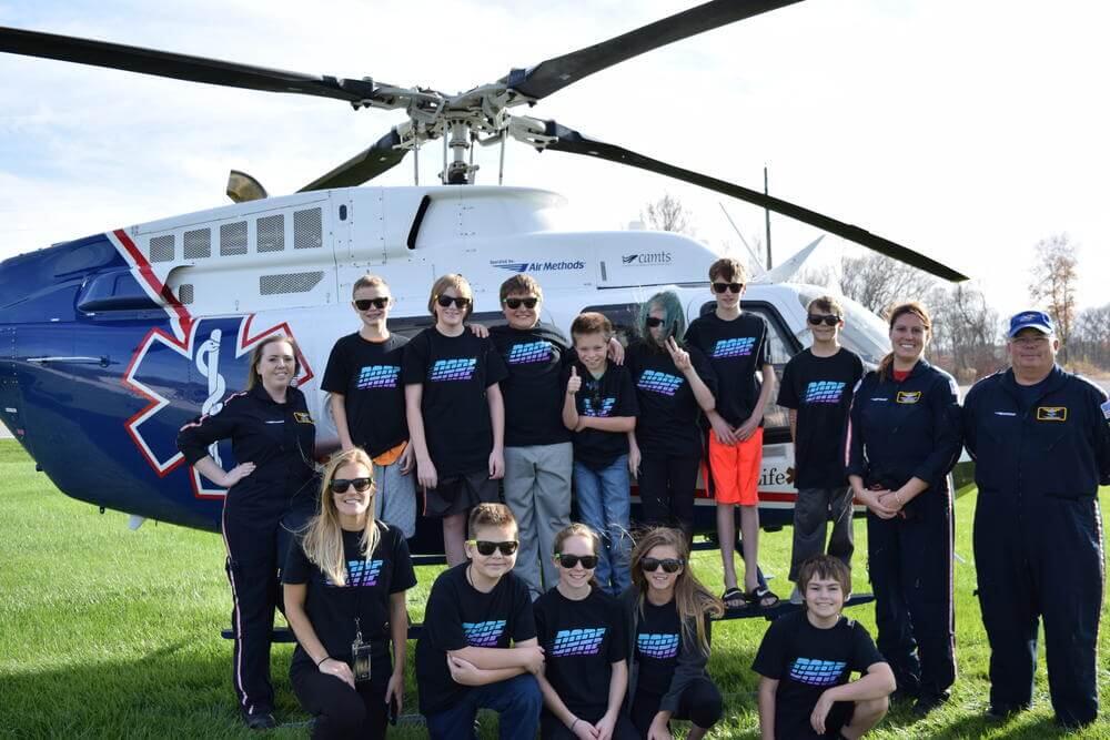 Young students gather around a helicopter that is used for medical transport.