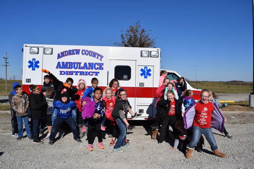 Young students gather around an Andrew County Ambulance.