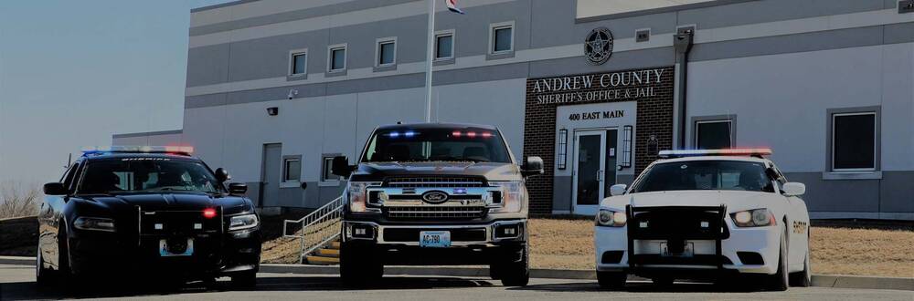 3 sheriff vehicles parked in front of the Andrew County Sheriff's Office and Jail entrance.